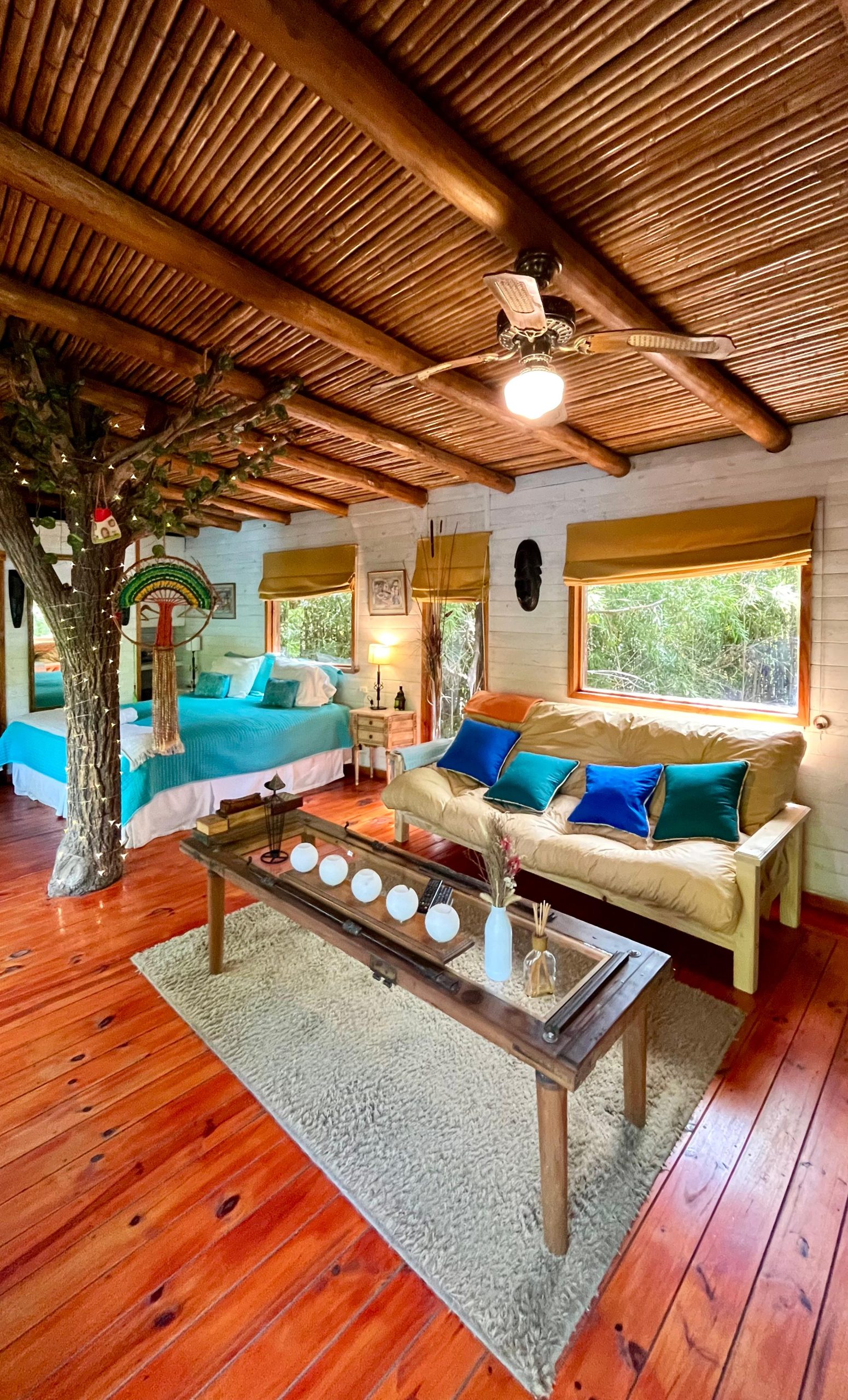 Living de la cabaña con el tronco de un árbol atravesando el ambiente