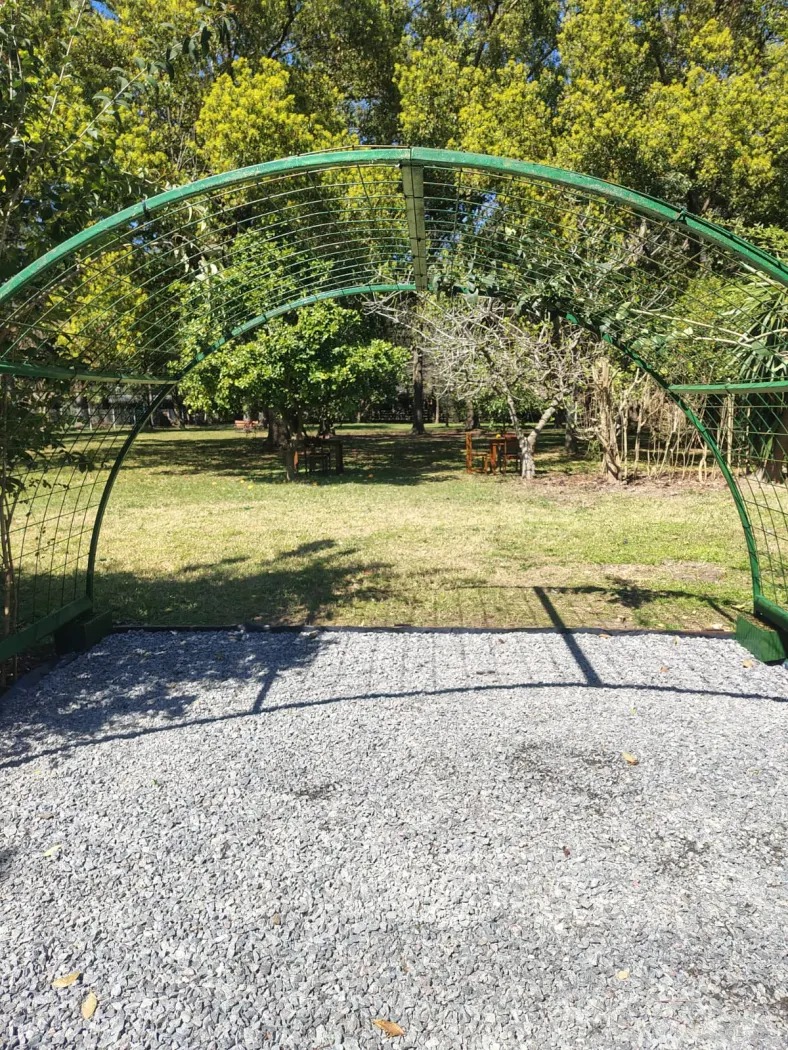 Arco de entrada al bosque encantado, con el parque arbolado detrás