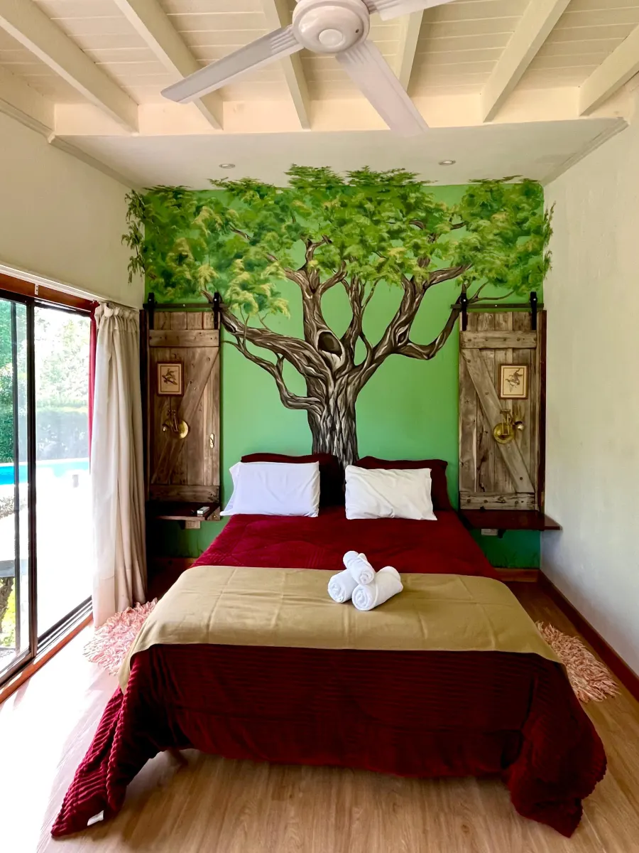 Cama de la suite El Ombú, con el ombú pintado en la pared